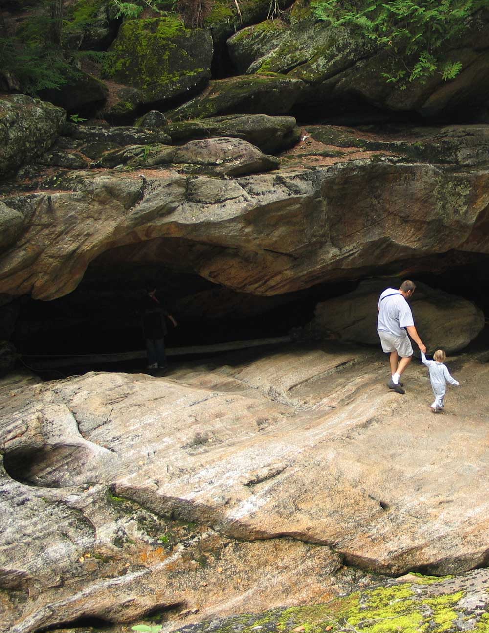 man and daughter walk by cave entrance