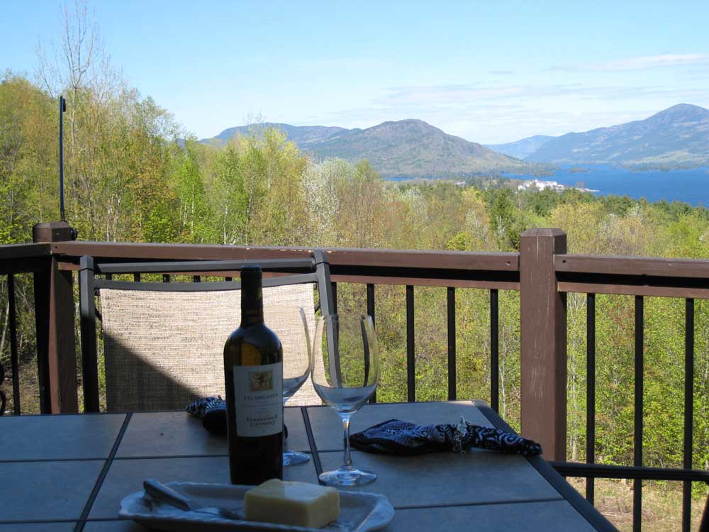 bottle of wine and cheese on porch table looking at adirondacks