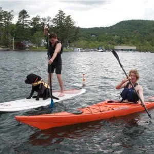 two men and a dog on kayak and stand up paddleboard